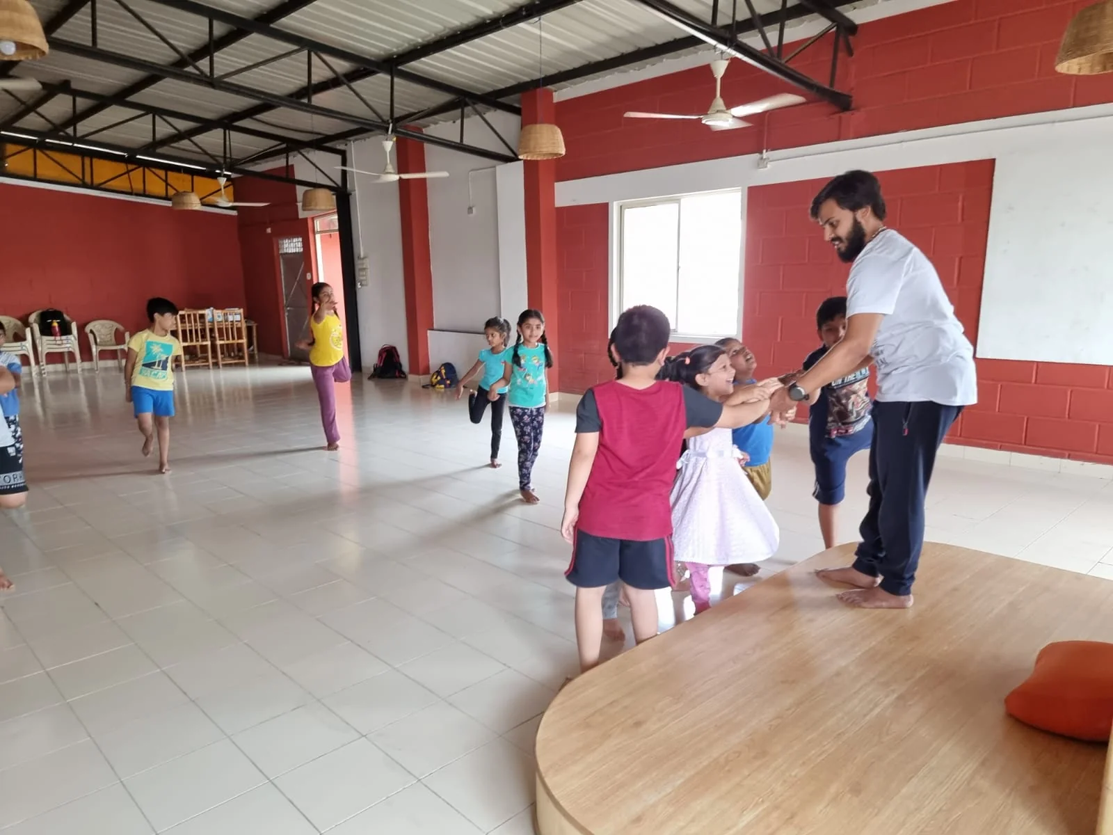 Gandharva teaching a children's yoga class on the studio's wooden platform