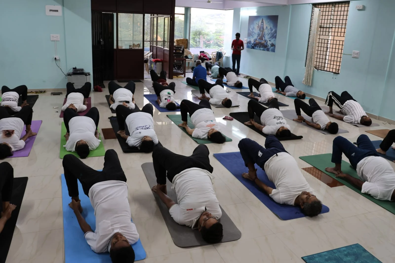 A mixed-age group of students in plow pose