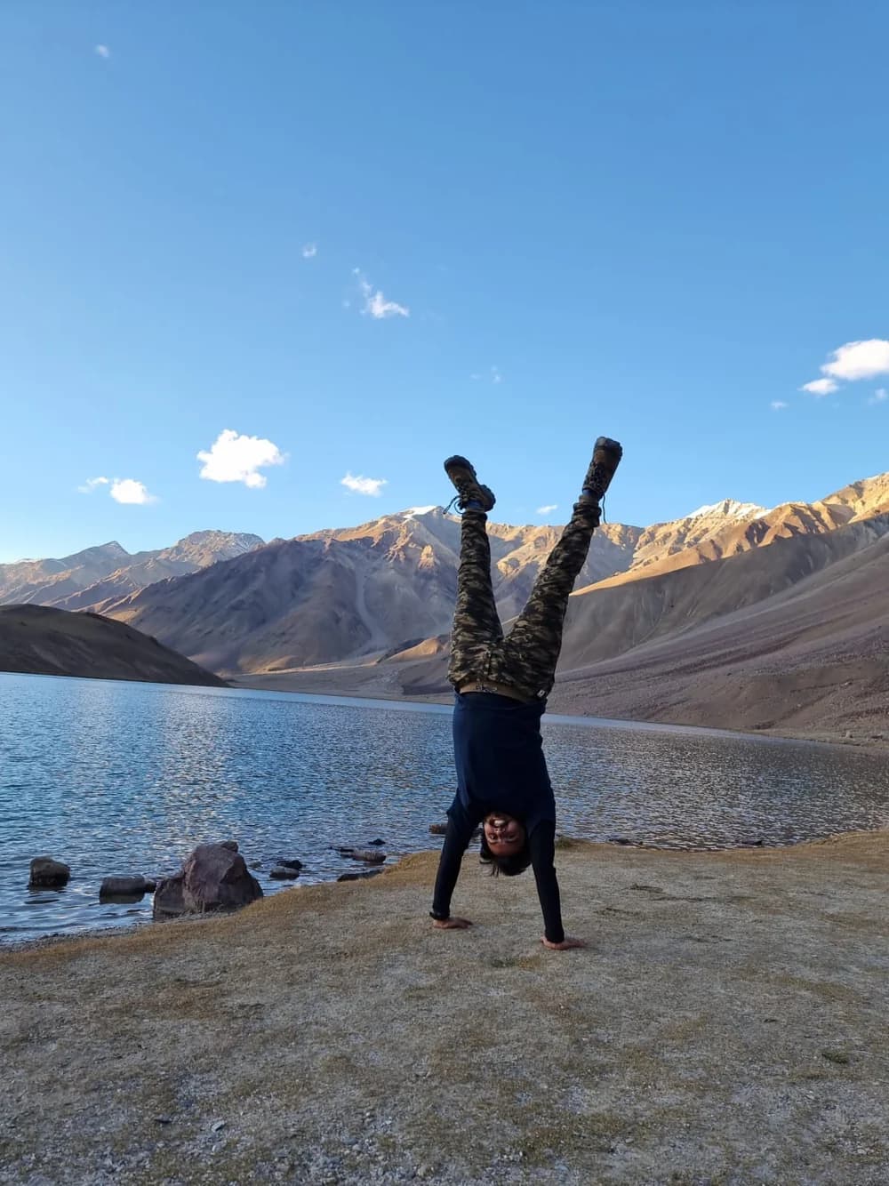 Gandharva in a handstand beside a mountain lake in Ladakh