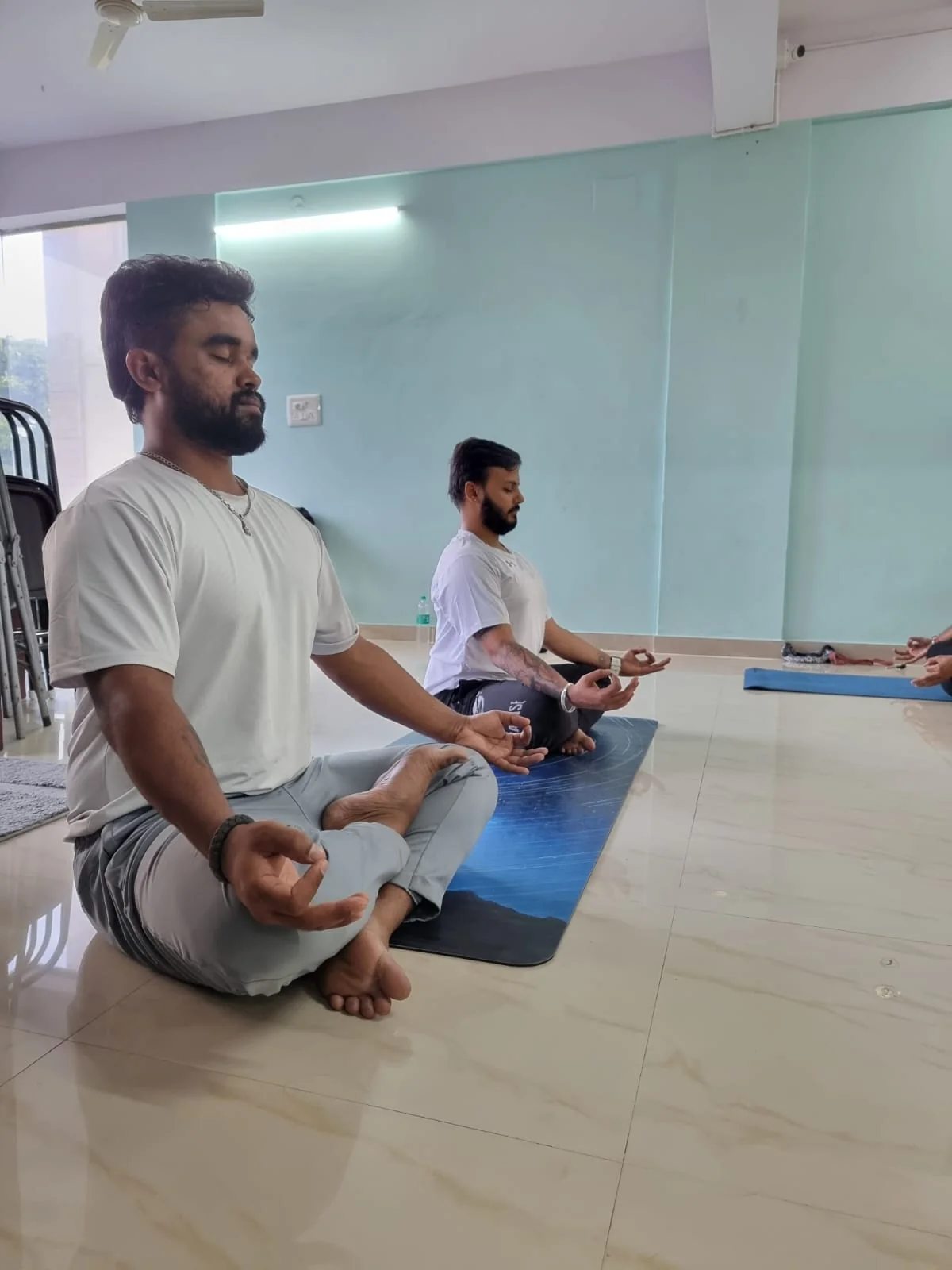 Two men meditating closely together in window light